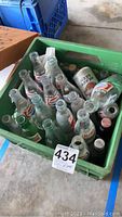 Top-down view of green crate filled with vintage glass soda bottles including Pepsi, Diet Coca-Cola, Coca-Cola and Mountain Dew, along with one beer bottle.