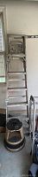 Full view of the 6ft aluminum ladder leaning against a wall, showing its height and construction.