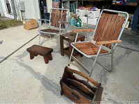 Wide shot showing both metal frame chairs with wooden slats, foot step stool, magazine rack, and side table arranged outdoors.