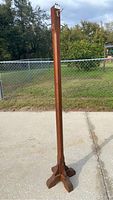 Full view of the wood hall tree standing outdoors on a concrete surface, showing its height and wooden base structure.