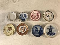 Top view of 8 assorted mini antique china plates arranged in two rows, showing varied designs and colors.