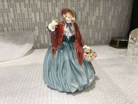 Front view of Royal Doulton Lady Charmian figurine in blue dress with red cloak and bonnet, holding flowers and basket
