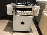 Front view of Yamaha AV receiver placed on top of subwoofer with cables on top