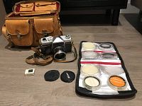 Front view showing tan leather-canvas bag, Kowaflex SLR camera with lens and strap, folded filter wallet, two lens caps and small Sekonic meter component