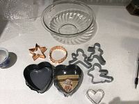 Clear glass Pyrex mixing bowl, 6 cookie cutters in various shapes, and 2 black heart-shaped release pans shown on countertop.