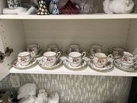 Full view of 8 teacups and saucers displayed on shelf, white china with floral and gold trim