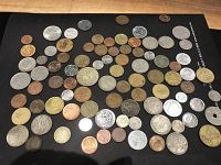 Two photos showing around 100 diverse coins spread out on a surface, coins vary in size, color and condition.
