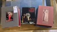 Top view of grey, pink and black hardcover art books placed flat, showing front covers