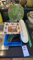 Photo showing five trays and platters including a green candy cane themed tray, a ceramic square Christmas plate with Santa, white elongated platter, blue and black rectangular trays.