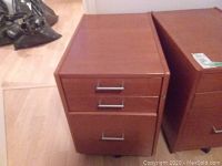 Faux wood finished filing cabinet front view showing three drawers with metal handles.