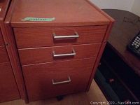 Front view of closed filing cabinet showing three drawers and metal handles