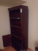 Full view of brown laminate bookcase showing adjustable shelves and open lower cupboard door