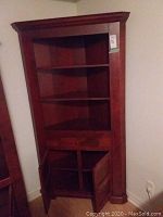 Front view of solid cherry corner bookcase showing three open shelves and drawer.