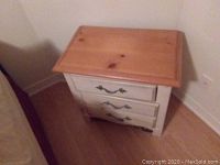 Front view of one pine topped painted wood nightstand with three drawers and metal pulls