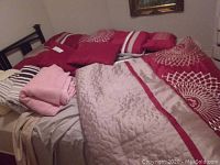 Photo showing queen bed with beige and red comforter and red throw cushions