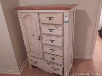 Front view of painted wood armoire with six drawers and door cupboard, showing metal pulls and distressed cream paint finish with natural wood top.