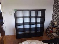 Front view of the black laminate 16-cube shelf unit showing 4 rows and 4 columns of storage cubes.