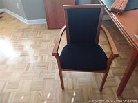 Photo of one wood framed chair with black fabric upholstery on seat and backrest, showing front view.