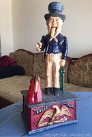 Front view of Uncle Sam cast iron bank showing painted figure standing on base with eagle detail.