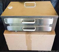 The closed steamer showing rectangular shape, two sliding drawers and top lid with handle and vent knob.