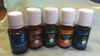 Photo showing five sealed 15ml bottles of Young Living essential oils, including Oregano, Clove, Eucalyptus, Cedarwood, and Basil.