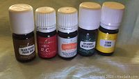 Photo showing five sealed Young Living essential oil bottles lined up: Black Pepper, R.C., Carrot Seed Vitality, Spearmint, and Lemon, each 5ml.