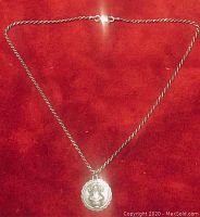 Full view of the 16 inch sterling silver twist chain necklace with attached medallion pendant displayed on red background.