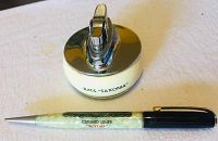 Close-up of the RMS Saxonia lighter showing cream base, chrome top, and inscription.