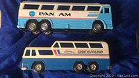 Side view of two vintage toy buses: Pan Am Shuttle Bus on top and Greyhound Scenic Cruiser on bottom, showing colors and decals.