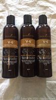 Three bottles of Young Living V-6 Vegetable Oil Complex lined up, showing front label and packaging in detail.