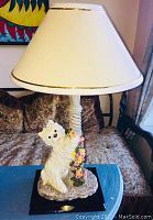 Table lamp with cream shade and Scottish Terrier figurine climbing floral vine on base, full front view.