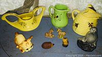 Full lot of vintage porcelain items including creamer, pitcher, honey pot, and animal figurines arranged on table.