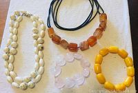 Photo of five polished stone jewelry pieces: three necklaces and two bracelets, showing colors and stone types.