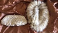 Ivory vintage sequin clutch purse alongside a mink tail hat on a brown fabric background.