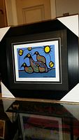 Framed and matted art print showing colorful stylized loons with sun and abstract elements.