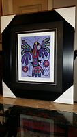 Photo of professionally framed and matted colorful Thunderbird print by Norval Morrisseau with black frame and protective corner covers