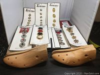 Two wooden shoe stretchers and 15 decorative button covers on cards laid out on a black surface.