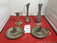 Front view of five metal and silverplated decorative pieces including two round candle holders, one single candle holder, and two vases