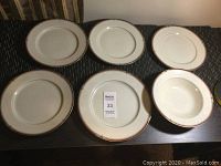 Six pieces of Oscar De La Renta china including dinner plates and smaller plates or bowls arranged on a table showing the overall set condition.