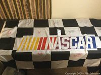 Full view of the NASCAR checkered flag with visible signatures and NASCAR logo.