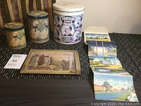 Overview of all items showing three tins, postcards, and the thermometer