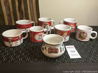 Seven vintage Campbell Soup mugs arranged in a line on a black patterned mat.