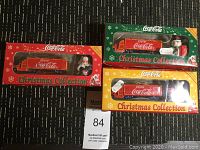 Lot of three boxed Coca Cola Christmas collectible porcelain trucks with Santa figurines; red, green, and yellow themed boxes.