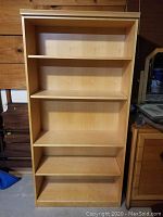 Front view of the wooden bookcase showing four shelves and light wood finish.