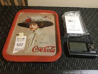 Overview showing the tin tray, new atomic Coca Cola clock with its instructions on a table.