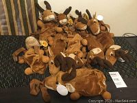 Ten brown reindeer plush kids backpacks displayed on floor, showing variety and grouping.