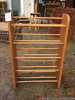 Front view of wooden blanket holder rack showing all horizontal bars and side panels.
