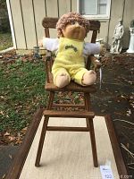 Front view of the vintage wooden high chair with Cabbage Patch Kid doll seated.