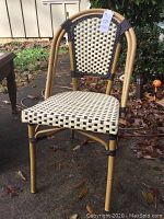 Front side angle view of the woven outdoor chair showing the light brown tubular frame and checkered seat and backrest.