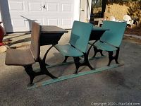 Side view of three vintage school desks mounted on a metal rail, showing voting seats with two green laminate seats and one natural wood seat in front.